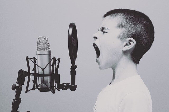 Imagen de un niño cantando frente a un micrófono