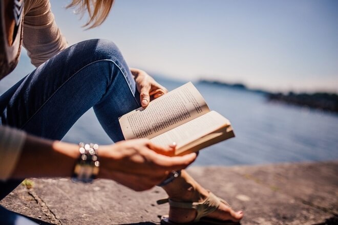Imagen de una persona leyendo un libro en el exterior